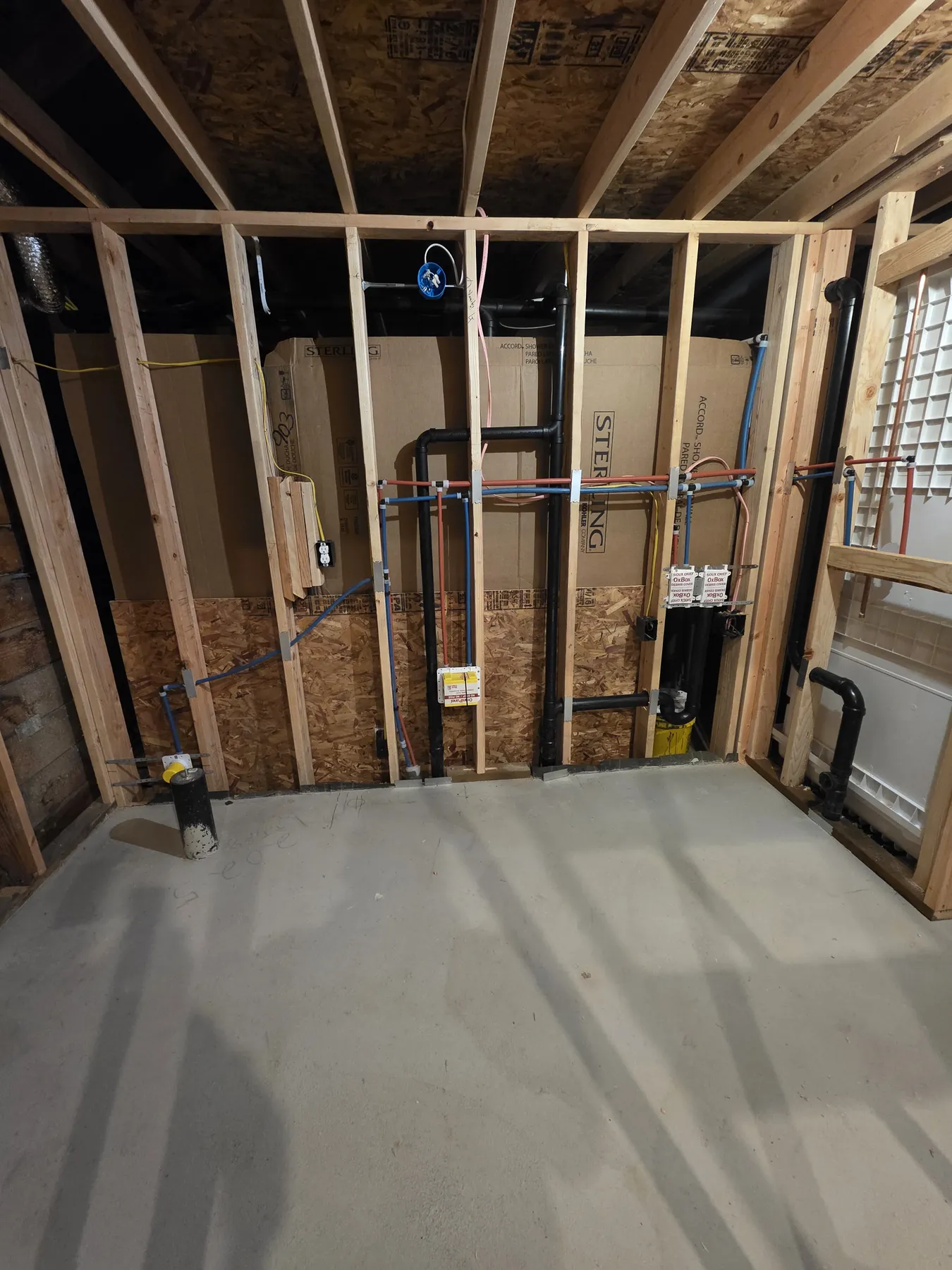 Rough-in plumbing run through an open stud wall in a framed room