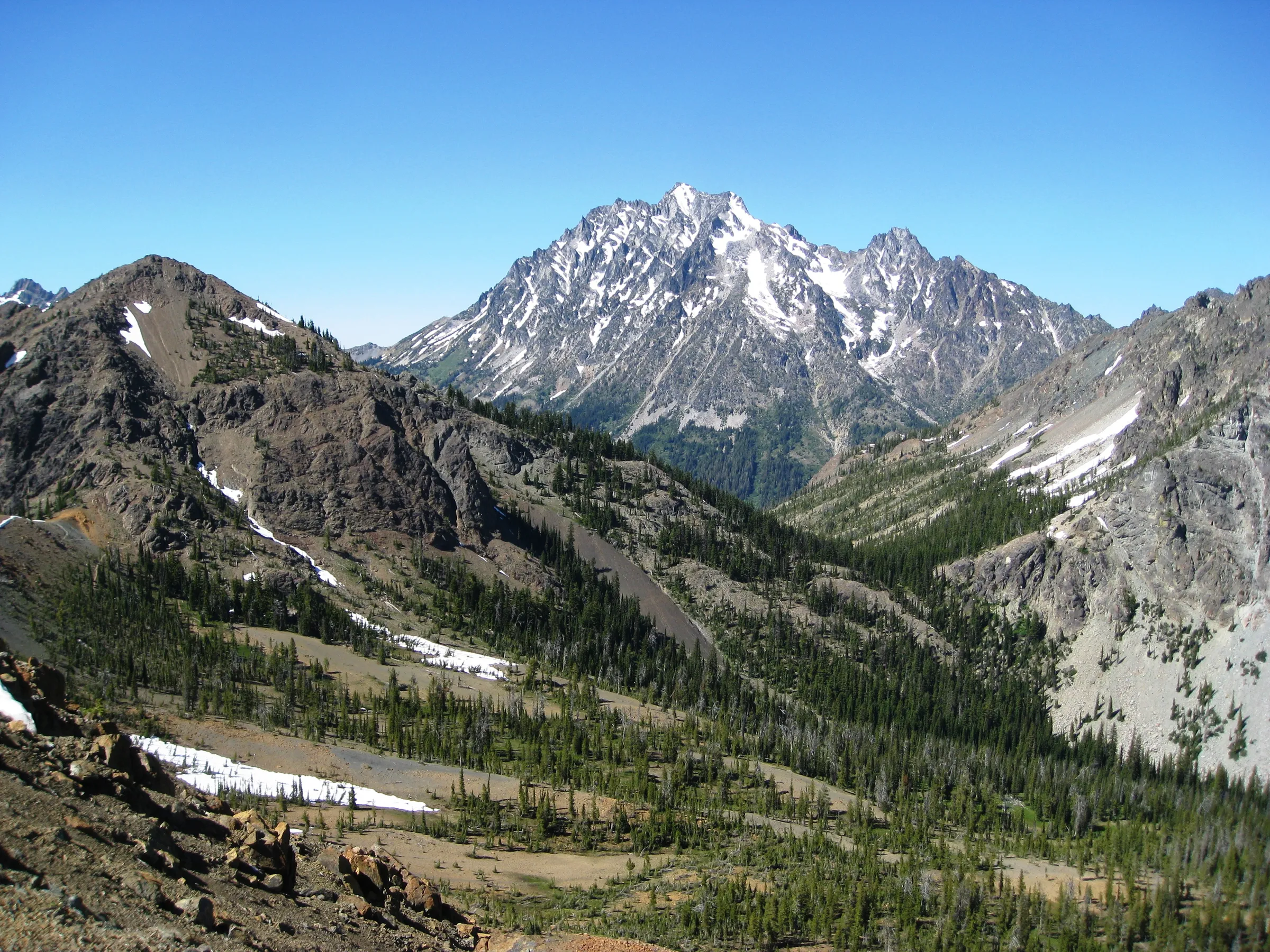 Mount Stuart seen from Iron Peak, snow on the summit above forested ridges